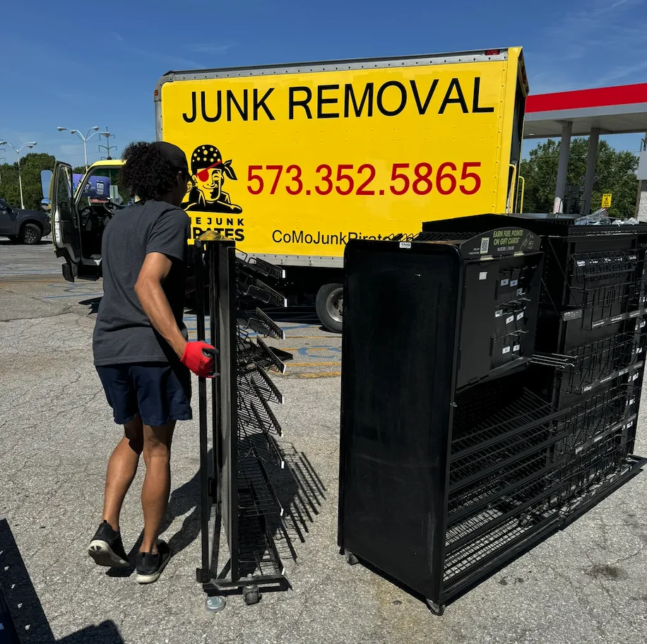A Junk Pirates crew member unloading stacked metal shopping carts and pallets from the company truck on a Columbia, MO commercial job.