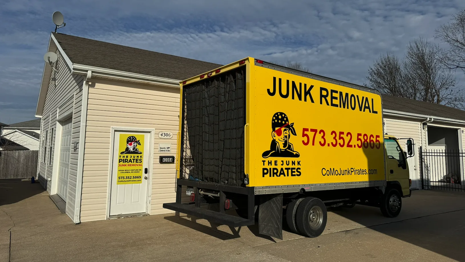 The Junk Pirates yellow box truck parked outside the company's local shop and yard in Columbia, MO.