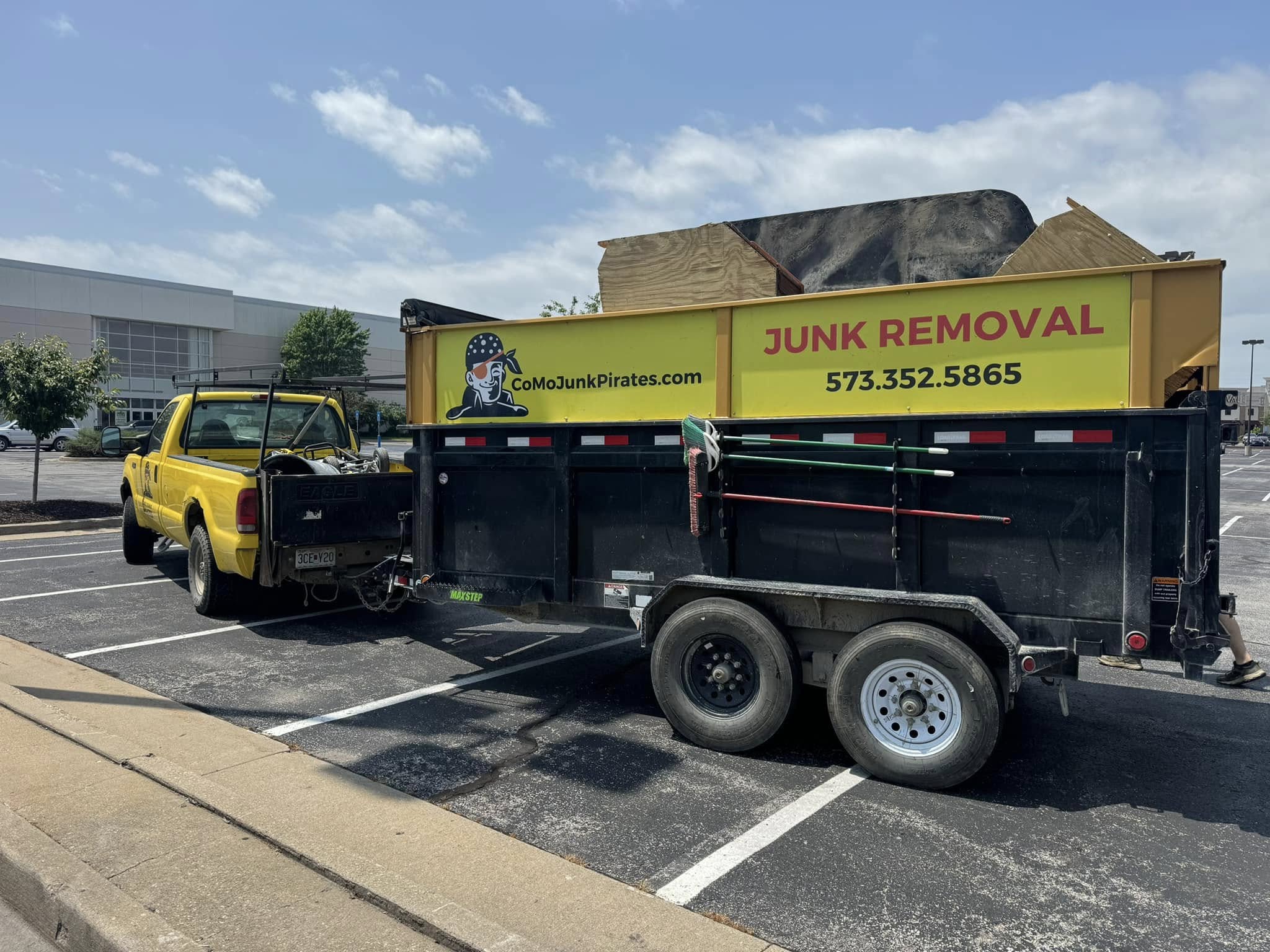 The Junk Pirates branded yellow truck and dump trailer loaded with a Columbia, MO job.